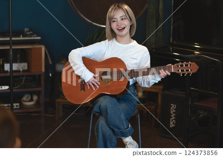 年輕女子在錄音室唱歌和彈奏原聲吉他 124373856