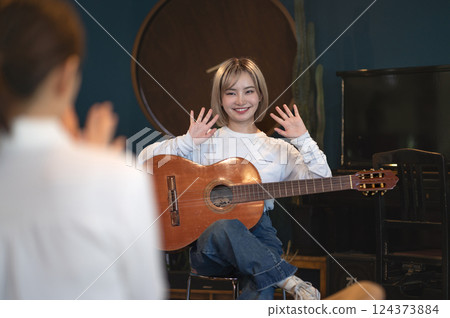 Young woman singing and playing an acoustic guitar in a studio 124373884