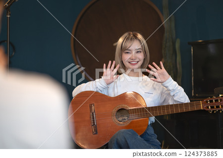 Young woman singing and playing an acoustic guitar in a studio 124373885