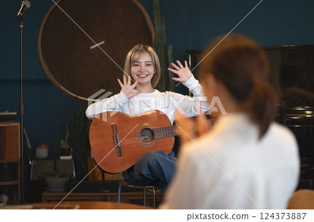 Young woman singing and playing an acoustic guitar in a studio 124373887