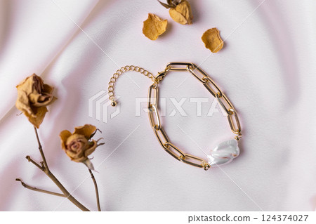 Jewelry on satin fabric with gold pearl bracelets and dry flowers elements. Handmade bijouterie and natural aesthetics in fashion 124374027