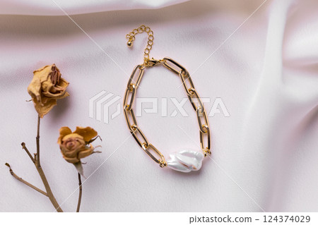 Jewelry on satin fabric with gold pearl bracelets and dry flowers elements. Handmade bijouterie and natural aesthetics in fashion Jewelry on satin fabric with gold pearl bracelets and dry flowers elements. Handmade bijouterie and natural aesthetics in fashion 124374029