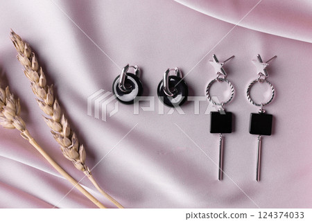 Female Jewelry. Vintage bijouterie jewelry. Beautiful handmade silver earrings on pink silk background. Flat lay, top view copy space and empty space for text Female Jewelry. Vintage bijouterie jewelry. Beautiful handmade silver earrings on pink silk background. Flat lay, top view copy space and empty space for text 124374033