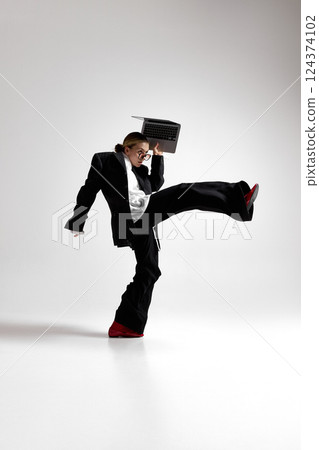 Full-length shot of professional woman balancing laptop in motion in one hand and make big step, embodying challenges of remote work. Full-length shot of professional woman balancing laptop in motion in one hand and make big step, embodying challenges of remote work. 124374102