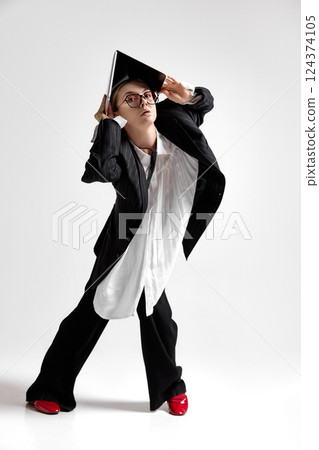 Quirky professional in stylish black suit using laptop as makeshift shelter, illustrating struggle with work stress, need for workplace flexibility. Quirky professional in stylish black suit using laptop as makeshift shelter, illustrating struggle with work stress, need for workplace flexibility. 124374105