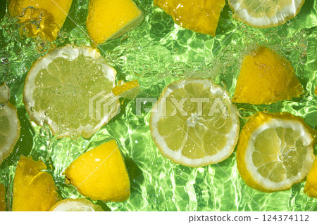 Slices of fresh lemons in water, splash of water, fresh green background, top view 124374112