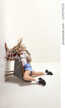Modern employee juggling work and exhaustion, collapsed over chair, struggling to balance responsibilities. Rotated shot. 124374153