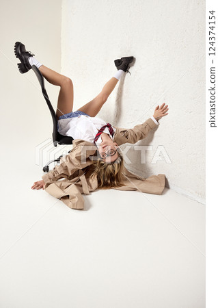 Full-length dynamic image of young blonde woman, employee, dressed in stylish attire, interacting with workspace space in unconventional pose. Full-length dynamic image of young blonde woman, employee, dressed in stylish attire, interacting with workspace space in unconventional pose. 124374154