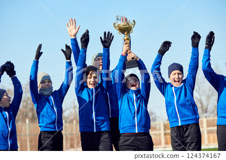 Champions Moment. Youth soccer players lifting golden trophy, cheering with excitement and pride. Pure happiness. Champions Moment. Youth soccer players lifting golden trophy, cheering with excitement and pride. Pure happiness. 124374167