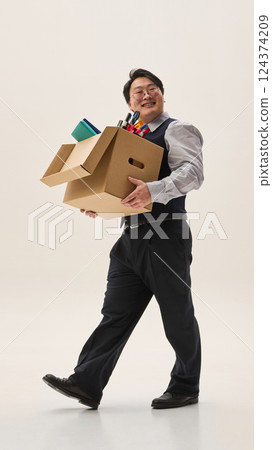 Overjoyed young Asian man, dressed formal attire, carrying huge cardboard box with clothes, and quitting job against white background. 124374209