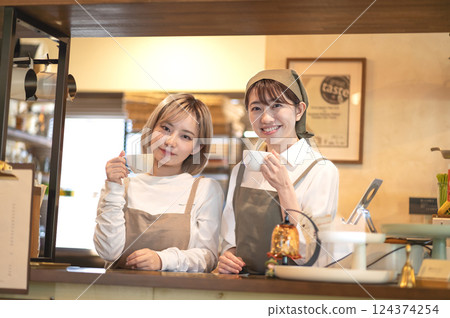 Two female baristas holding coffee cups at the counter Two female baristas holding coffee cups at the counter 124374254