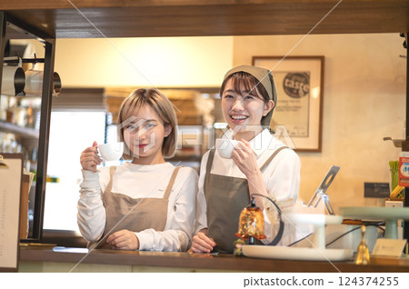 Two female baristas holding coffee cups at the counter Two female baristas holding coffee cups at the counter 124374255