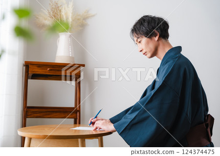 Quiet moment - Man in traditional Japanese clothing writing a letter 124374475