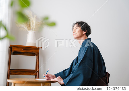 Quiet moment - Man in traditional Japanese clothing writing a letter Quiet moment - Man in traditional Japanese clothing writing a letter 124374483