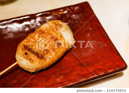 close up of grilled skewer of Mashed Cuttlefish wrapped with chicken skin on a red plate 124374834