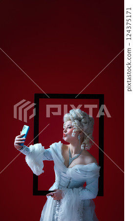 Digital duchess. Medieval woman in rococo style holding smartphone and taking selfie, framed in art history Digital duchess. Medieval woman in rococo style holding smartphone and taking selfie, framed in art history 124375171