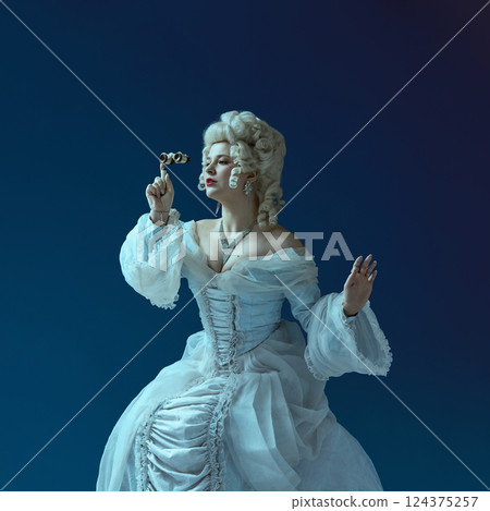 Curious gaze. Woman dressed in rococo style holding antique opera glasses, exuding playful curiosity 124375257