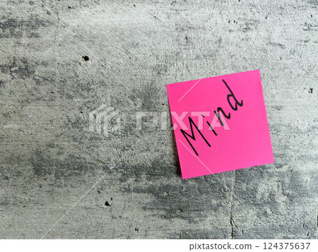 Vibrant pink sticky note with the word Mind placed on a textured grey background, representing mental clarity, focus, and the significance of mindfulness in personal and professional life 124375637