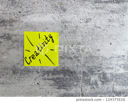Bright yellow sticky note displaying the word Creativity with decorative elements on a textured grey background, symbolizing inspiration and the power of imaginative thinking 124375638
