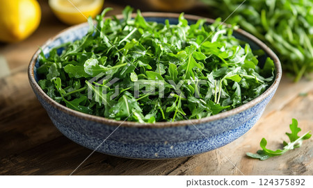 Fresh Arugula Leaves in Blue Bowl on Wooden Table 124375892