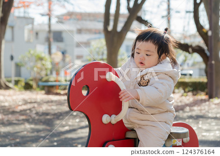 [A one-year-old child playing on playground equipment in a winter park] 124376164