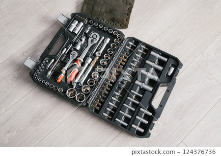 Comprehensive mechanic tool kit with ratchets, sockets, and wrenches on light wood floor Comprehensive mechanic tool kit with ratchets, sockets, and wrenches on light wood floor 124376736