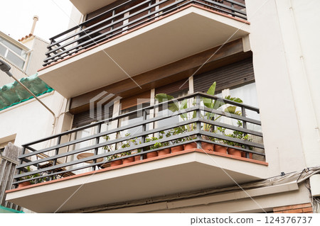 Modern apartment balcony with green plants and metal railings on residential building Modern apartment balcony with green plants and metal railings on residential building 124376737