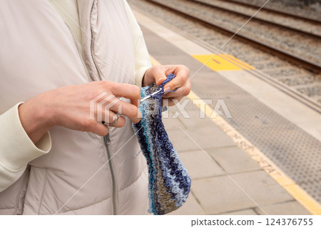 Female crocheting at train station platform on a calm day 124376755