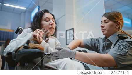 Security Worker Walks with Woman with Physical Disability to Security Checkpoint in Airport Terminal Security Worker Walks with Woman with Physical Disability to Security Checkpoint in Airport Terminal 124377395