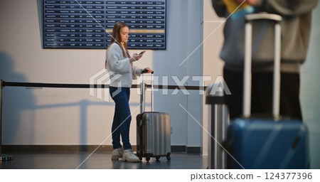 Crowded Airport Terminal: Woman Using Smartphone, Waiting for Flight Crowded Airport Terminal: Woman Using Smartphone, Waiting for Flight 124377396
