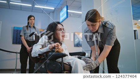 Female TSA Officer Checking Woman with Physical Disability in Airport Terminal Female TSA Officer Checking Woman with Physical Disability in Airport Terminal 124377404