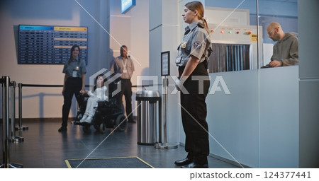 Security Checkpoint in Airport Terminal: Female Security Officer Inspecting Woman in Wheelchair 124377441