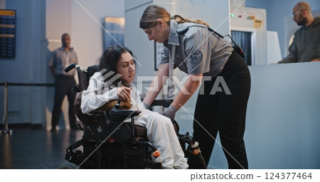 Security Checkpoint: Female TSA Officer Checking Woman with Physical Disability in Airport Terminal 124377464