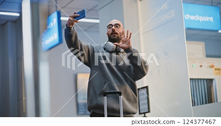 Crowded Airport Terminal: Tourist Talking on Phone by Video Call or Recording Video Content 124377467