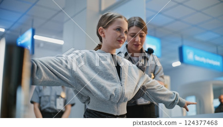 Security Checkpoint in Airport: Female TSA Officer Checks Girl, Conducts Screening Procedures Security Checkpoint in Airport: Female TSA Officer Checks Girl, Conducts Screening Procedures 124377468