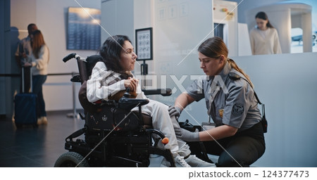 Security Checkpoint: Female TSA Officer Checking Woman with Physical Disability in Airport Terminal Security Checkpoint: Female TSA Officer Checking Woman with Physical Disability in Airport Terminal 124377473