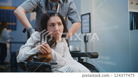 Security Checkpoint in Airport Terminal: Female Security Officer Inspecting Woman in Wheelchair 124377475