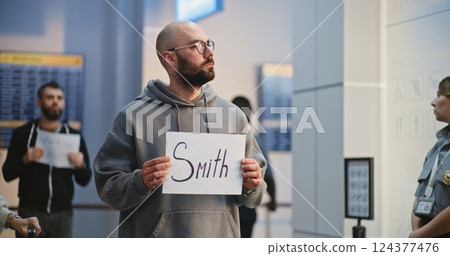 Transportation Service in Airport: Airport Greeter Holding Greeting Sign, Waiting for Passengers 124377476