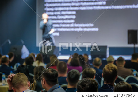 Speaker addressing audience with presentation on screen during business conference event Speaker addressing audience with presentation on screen during business conference event 124377649