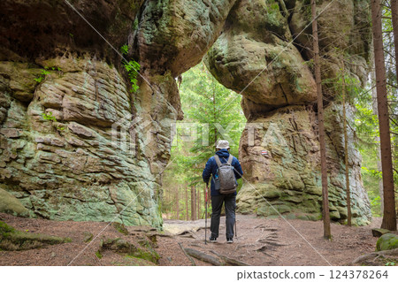 Man walks through natural stone gate in Stolowe Mountains 124378264