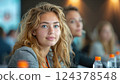 A blond woman with a big smile is sharing a plastic bottle of water at an event 124378548