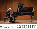 Pianist performing on stage, playing a keyboard instrument 124378555