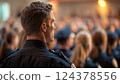 Police officer maintaining order in front of a large crowd at an event 124378556