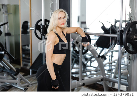 Athletic woman performing squats with barbell in gym Athletic woman performing squats with barbell in gym 124379051