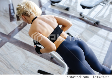 Athletic woman performing back extension exercise using hyperextension bench in gym Athletic woman performing back extension exercise using hyperextension bench in gym 124379056