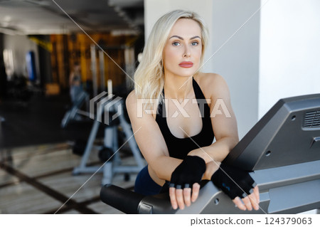 Determined sportswoman running on treadmill during fitness workout in gym Determined sportswoman running on treadmill during fitness workout in gym 124379063