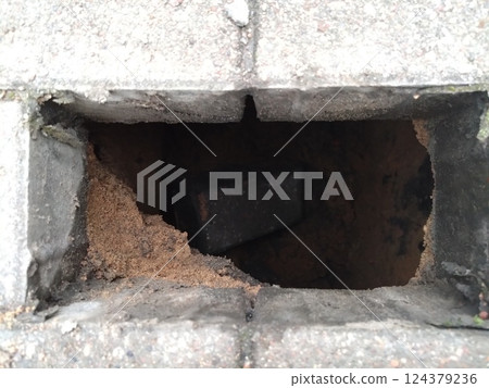 Close-Up of a Hole in a Paved Surface with Sand Inside Close-Up of a Hole in a Paved Surface with Sand Inside 124379236