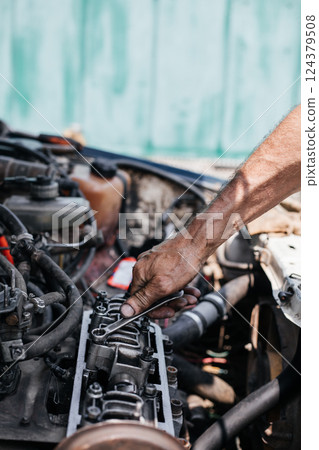 A worker repairs the cylinder head of an automobile engine. Oil removal valve. Car repairs. Car service A worker repairs the cylinder head of an automobile engine. Oil removal valve. Car repairs. Car service 124379508