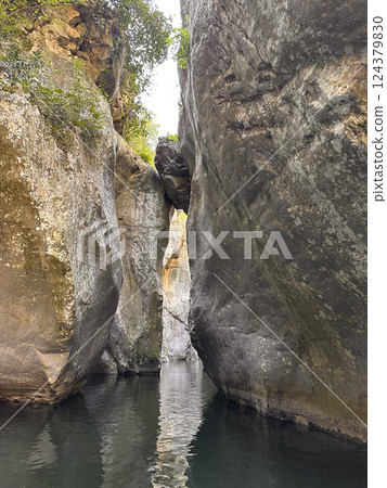 Majestic rock formations create a narrow passageway leading to tranquil waters in a stunning natural landscape concept Majestic rock formations create a narrow passageway leading to tranquil waters in a stunning natural landscape concept 124379830