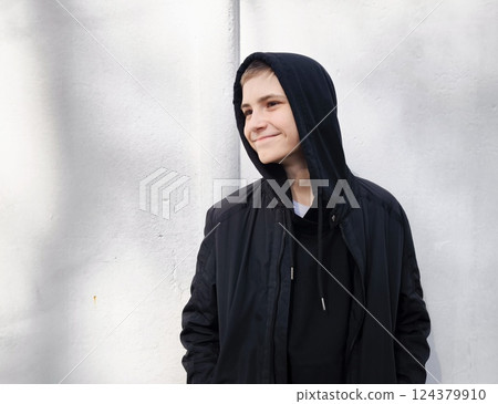Close-up young caucasian teenager guy smiling. Guy in a black hood outdoors. handsome young man Close-up young caucasian teenager guy smiling. Guy in a black hood outdoors. handsome young man 124379910